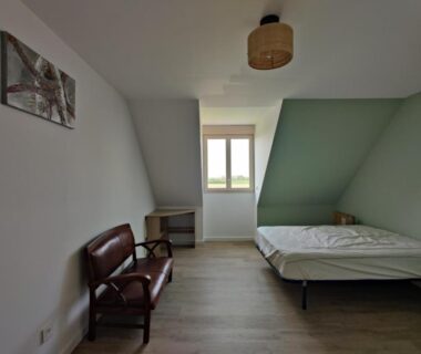 Chambre intérieure avec lit et fauteuil près de fenêtre dans le camping haipenée