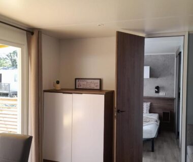 Séjour avec armoire et chambre visible dans le mobil-home du camping la carabasse