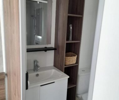 Salle d'eau avec lavabo et étagères dans le camping la carabasse