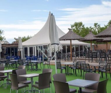 Terrasse extérieure avec tables et parasols au camping la carabasse