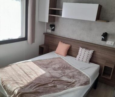 Chambre avec lit double et fenêtre au camping la carabasse