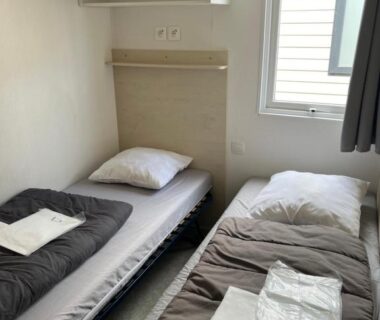 Chambre avec deux lits simples et fenêtre dans le camping les dunes 5 étoiles mobil home 6 personnes A16