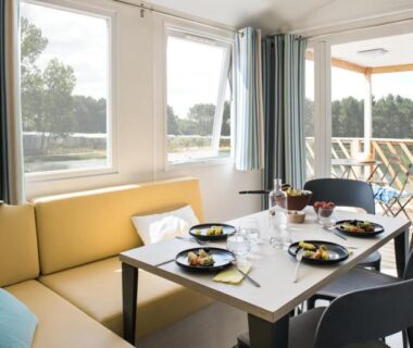 Séjour avec table dressée et terrasse donnant sur la nature au camping les pêcheurs