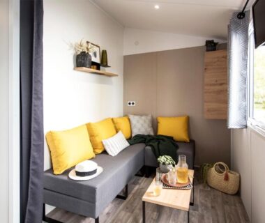 Intérieur avec canapé gris et coussins jaunes dans l'hébergement au camping les pêcheurs
