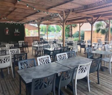Terrasse couverte avec tables et chaises au camping les sables du midi