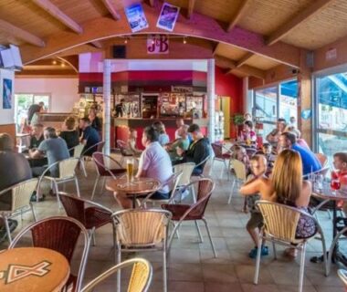 Bar intérieur et terrasse vitrée avec convives au camping sol a gogo 3 chambres