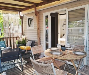 Terrasse en bois avec table et chaises devant porte-fenêtre du cosy mobil home forêt et plage