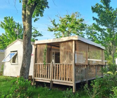 Terrasse en bois entourée d'arbres dans le cosy mobil home forêt et plage