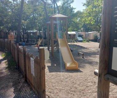 Aire de jeux avec toboggan et clôture en bois sous les pins dans le domaine de la sainte baume