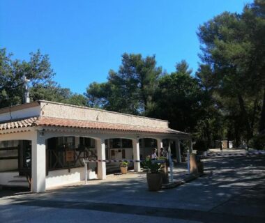 Bâtiment avec terrasse couverte et pins au domaine de la Sainte Baume