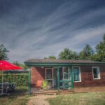 Dordogne chalet en bois avec terrasse et parasol rouge à l'hôtel gites le clos du moulin