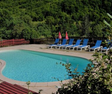 Piscine extérieure avec transats entourée de végétation à la Frégière Chalets