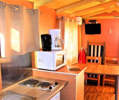 Intérieur kitchenette avec micro-ondes plaques et coin repas du chalet la Frégière