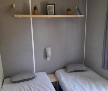 Chambre avec deux lits simples et étagère au camping la dune blanche