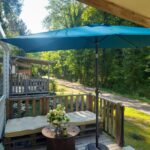 Terrasse en bois avec parasol et banquette au camping la dune blanche