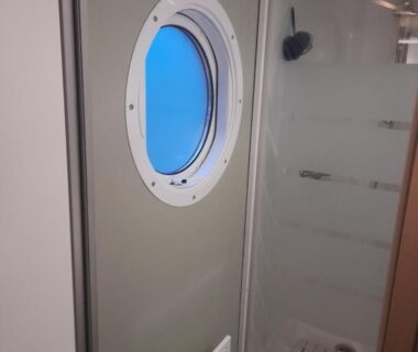 Salle de bain avec hublot et douche dans le camping La Dune Blanche