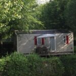 Terrasse avec table devant mobil-home entouré d'arbres à la ferme des 4 chenes