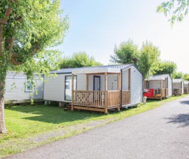 Allée de mobil-homes avec terrasse et pelouse au camping la ferme des 4 chenes