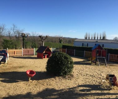 Aire de jeux sablonneuse avec cabanes et toboggan au camping la ferme des 4 chenes