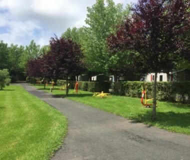 Allée du camping avec mobil-homes arbres et pelouse à la ferme des 4 chenes