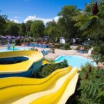Piscine extérieure avec toboggans et transats au Camping Des 3 Lacs