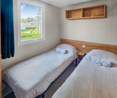 Chambre avec deux lits et fenêtre sur le camping le Nomatitoz