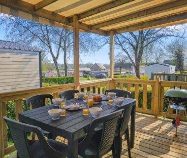 Terrasse en bois avec table dressée et barbecue au camping le Nomatitoz