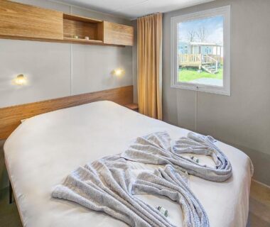Chambre avec lit double et serviettes pliées vue sur jardin au camping le Nomatitoz
