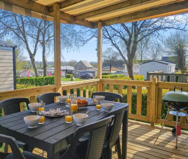 Terrasse en bois avec table dressée et chaises au camping le Nomatitoz
