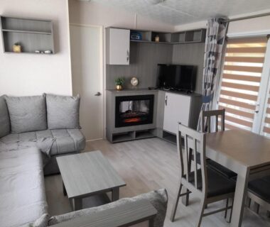 Séjour avec canapé table et télévision dans le mobile home Le Victory