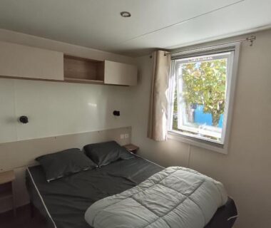 Chambre avec lit double et fenêtre donnant sur l'extérieur au camping les Dunes de Contis