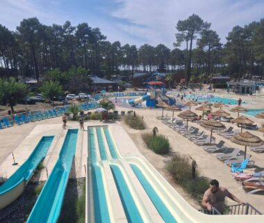 Piscine centrale avec toboggans et transats au camping les dunes de contis