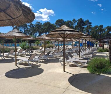 Bord de piscine avec transats et parasols au camping Les Dunes de Contis