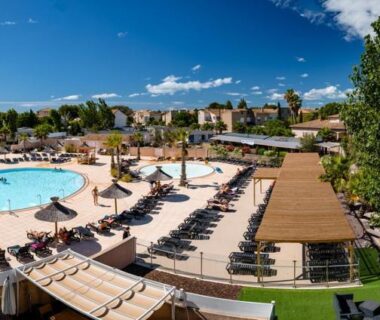 Bord de piscine avec transats et pergola au camping Les Sables du Midi Valras Plage