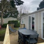 Terrasse en bois avec table chaises et transat du mobil-home l'impasse de la tranquillité