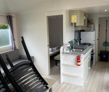 Coin cuisine avec chaises empilées dans le mobil-home l'impasse de la tranquillité