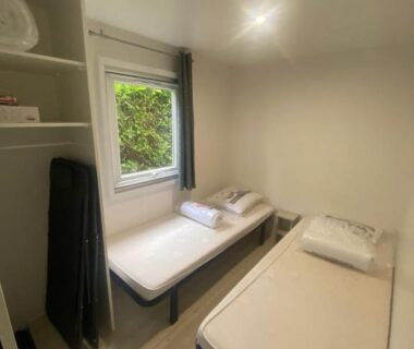 Chambre intérieure avec deux lits simples et serviettes pliées au camping l'impasse de la tranquillité