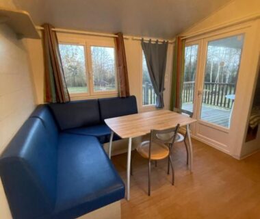 Coin repas dans mobil-home avec banquette et table dans le logement au coeur de la nature