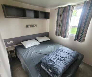 Chambre avec lit double et rideaux dans le mobil home