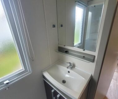 Salle de bain avec lavabo miroir et fenêtre dans le mobil home