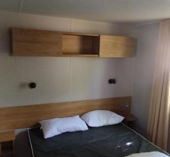 Chambre avec lit double et rangements dans le mobil home 235