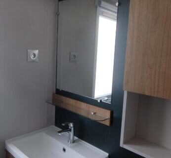 Salle d'eau avec lavabo et miroir dans le mobil home 235