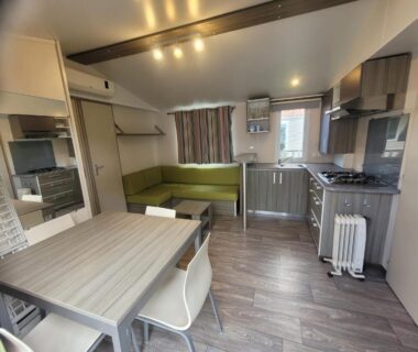 Intérieur avec coin repas canapé et kitchenette du mobil home