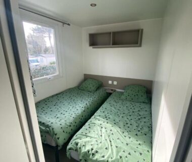 Chambre avec deux lits simples et fenêtre dans le mobil home 394 du Domaine de Kerlann
