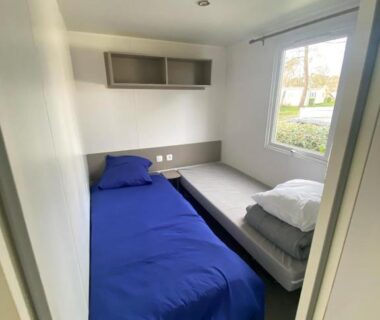 Chambre avec lit simple et couette bleue dans le mobil home 394 Domaine de Kerlann