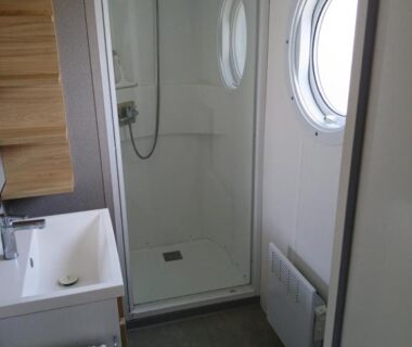 Salle d'eau avec cabine de douche et hublot dans le mobil home 4 personne