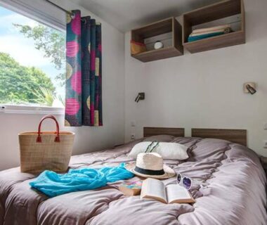 Chambre avec lit double chapeau et panier à côté dans le mobil home 6 pers du Domaine de la Pommeraie