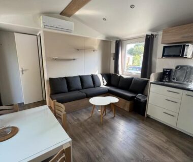 Salon avec canapé en L et kitchenette dans le mobil home 6 personnes accès direct plage