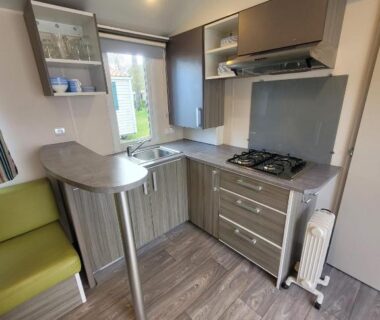 Cuisine compacte avec plaque de cuisson et coin repas dans le mobil home