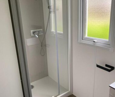 Salle d'eau avec cabine de douche et fenêtre dans le mobil home 742